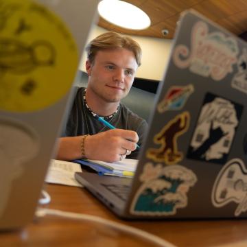 A student studies on his computer, which is covered in stickers.