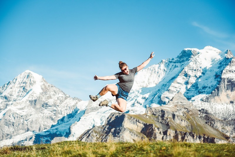 student jumping into the air in Sweden, snowy mountains behind 