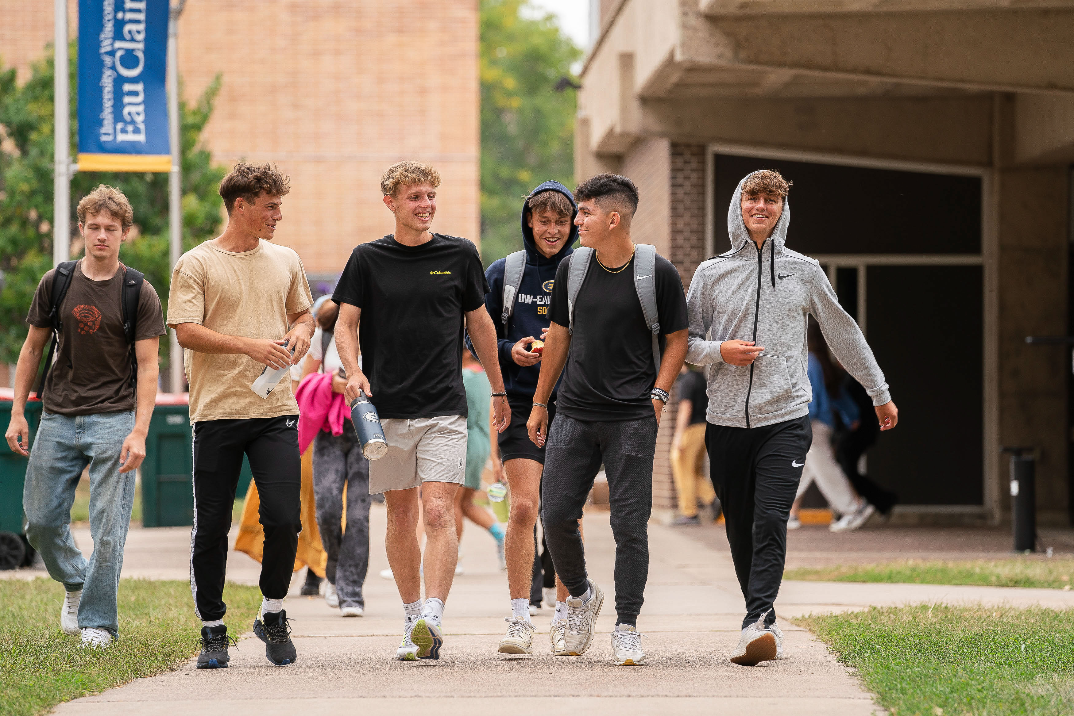 Students laughing and walking on the sidewalk on upper campus.