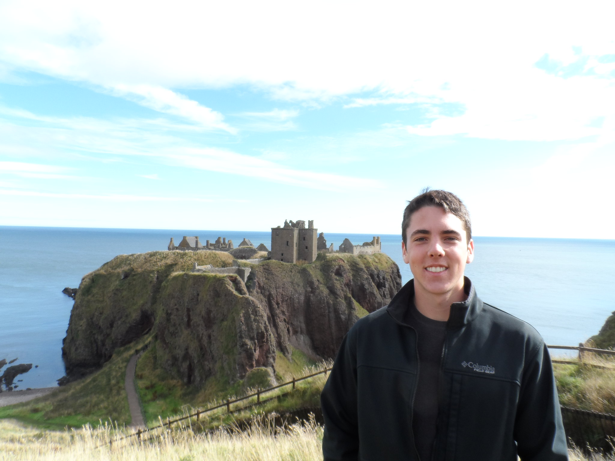 a picture of student during study aboard in Scotland in the foreground with the historic ruins of Dunnottar Castle