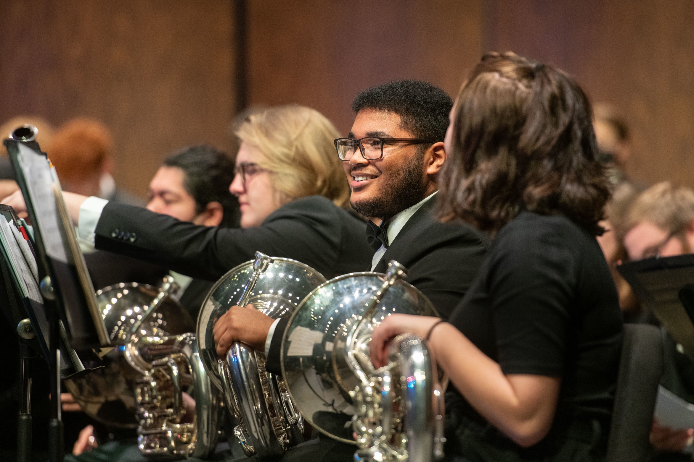 music students in horn section of orchestra during performance