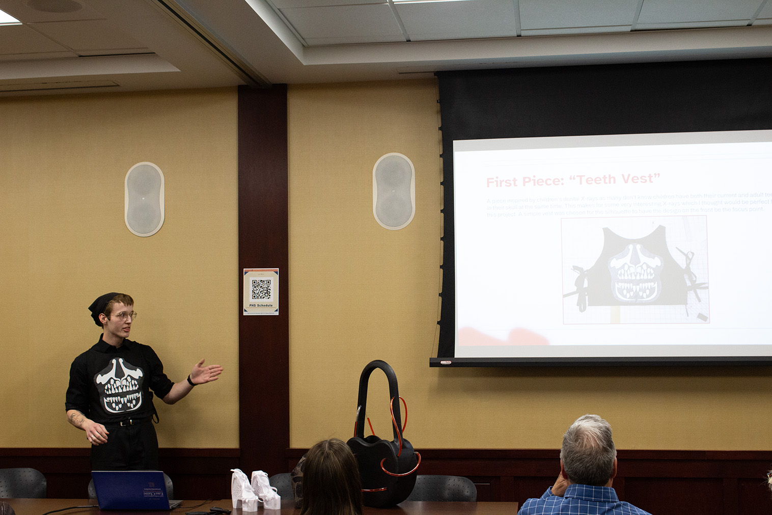 A student presents next to a large screen