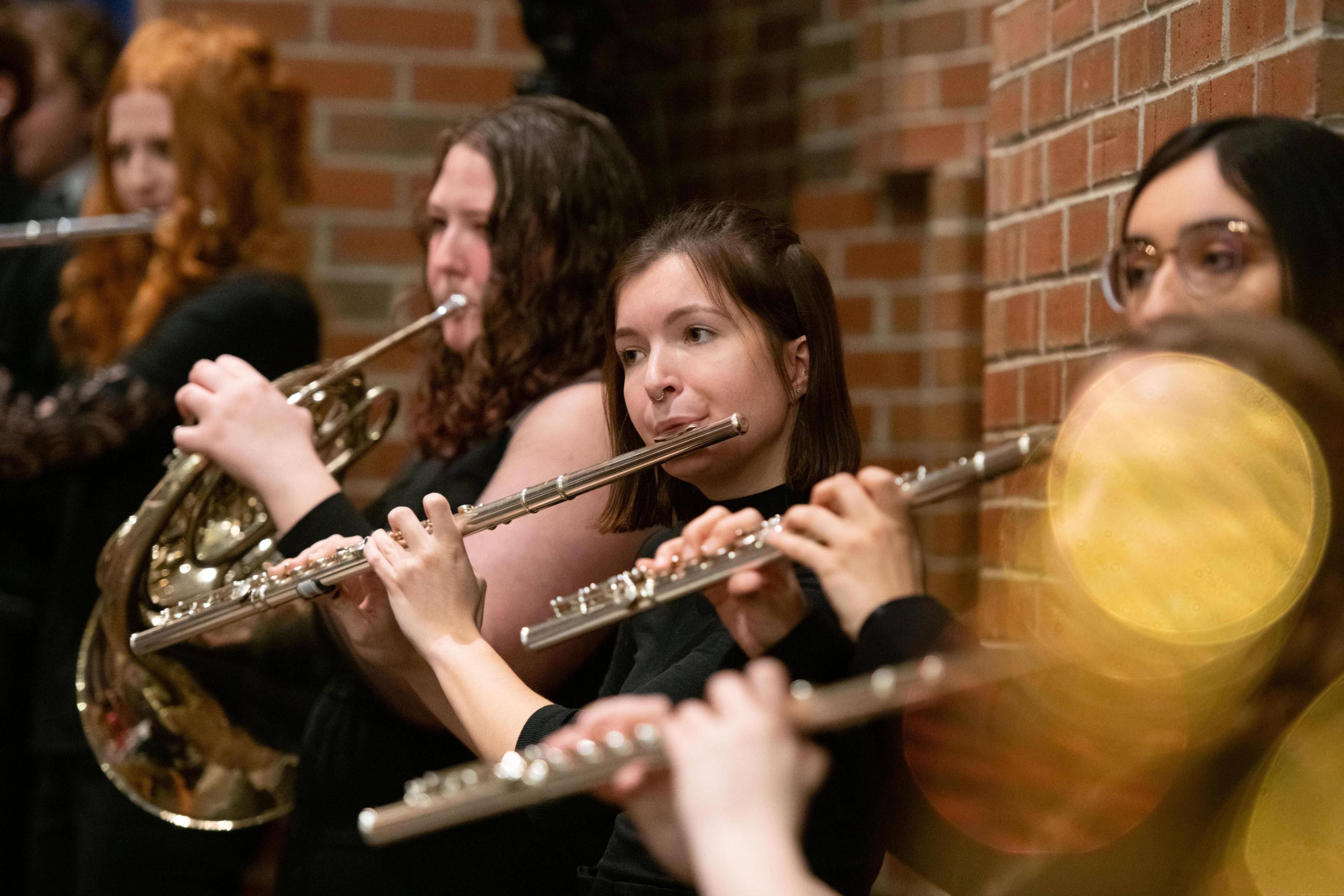 A group of students play their flutes at a musical performance.