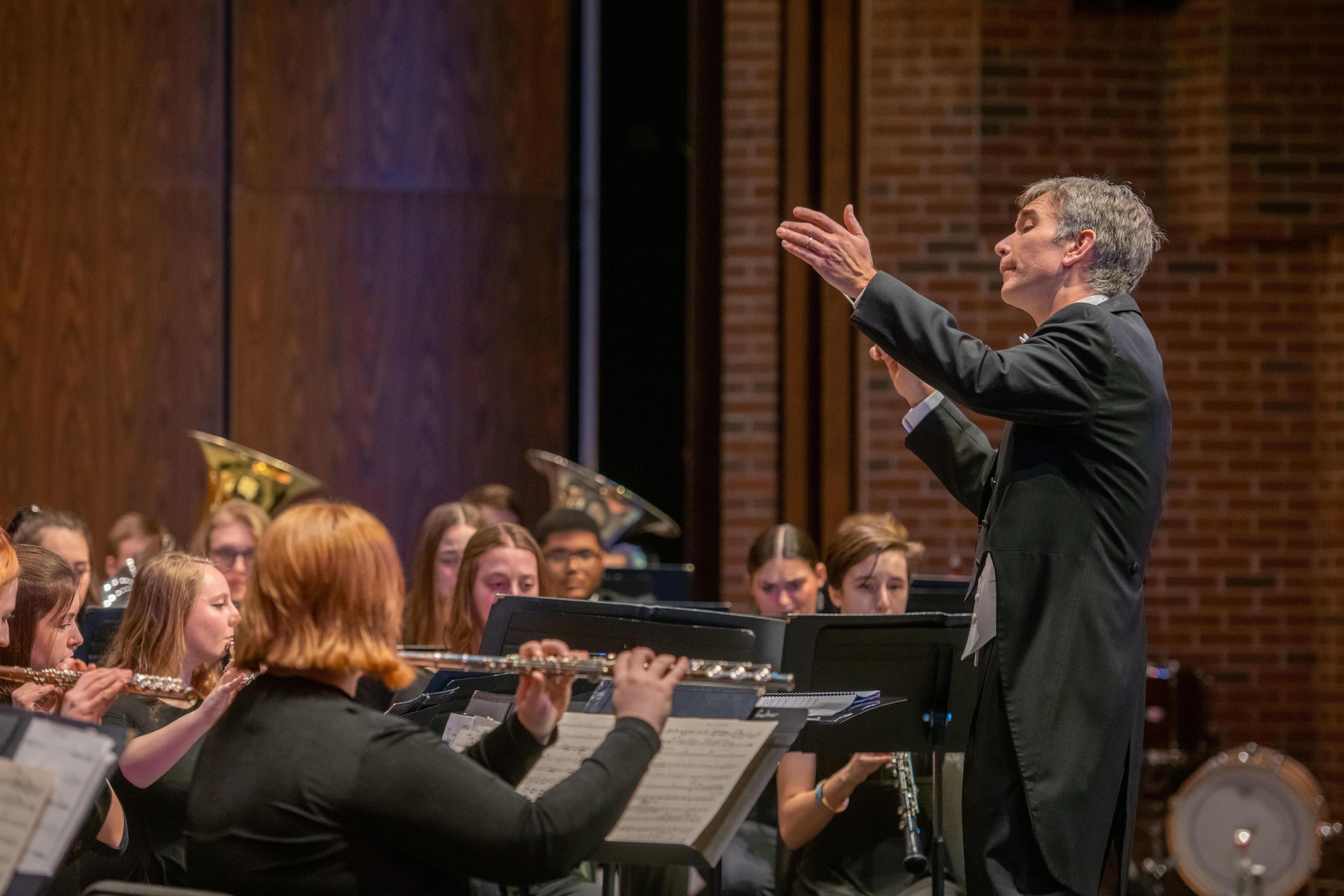 Person conducts an orchestra performance on stage