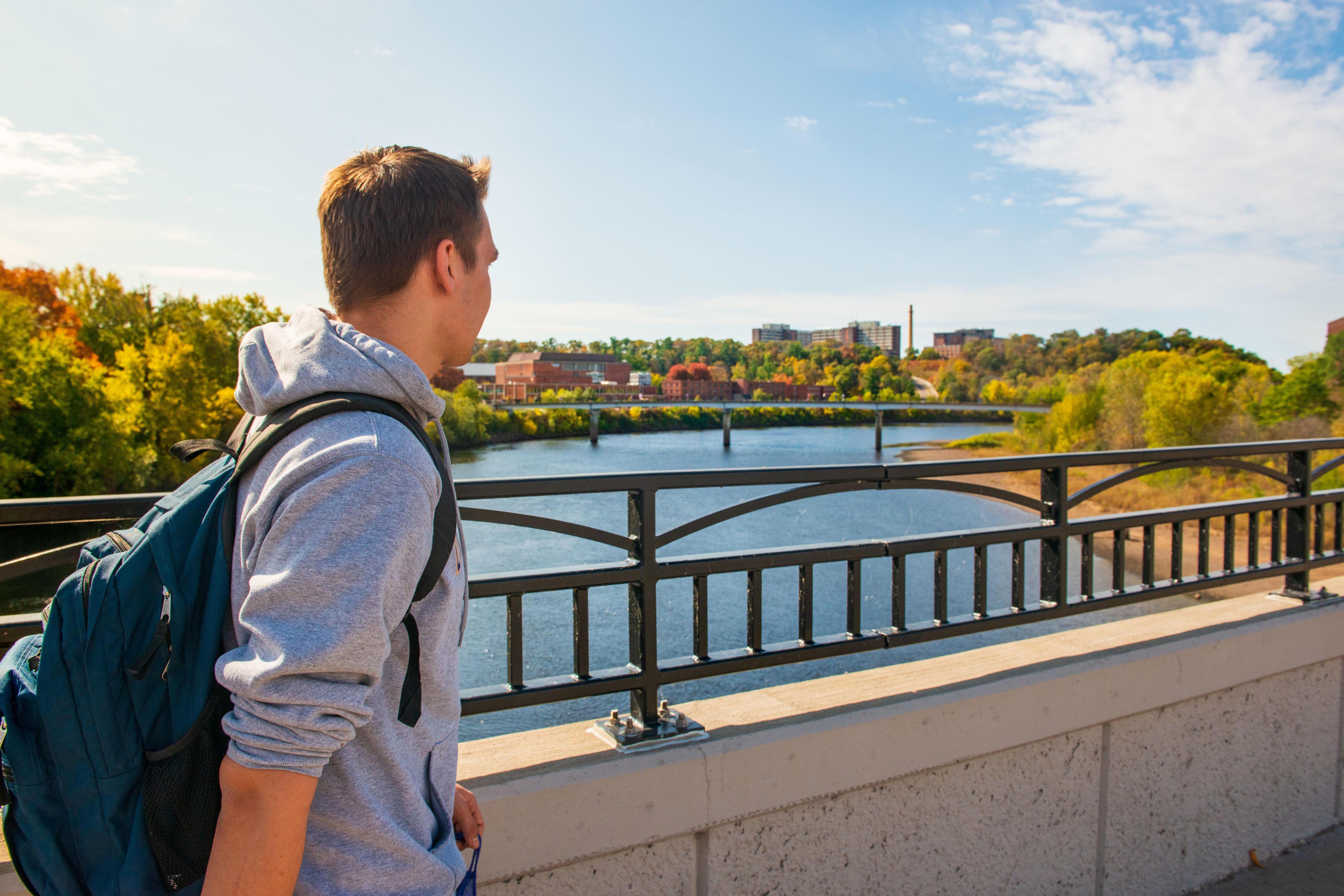 Student crosses foot bridge on a fall day.