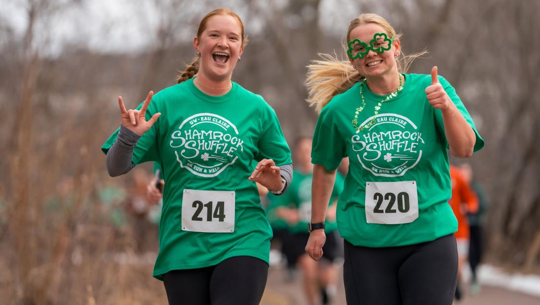 Two girls, one wearing shamrock glasses, running
