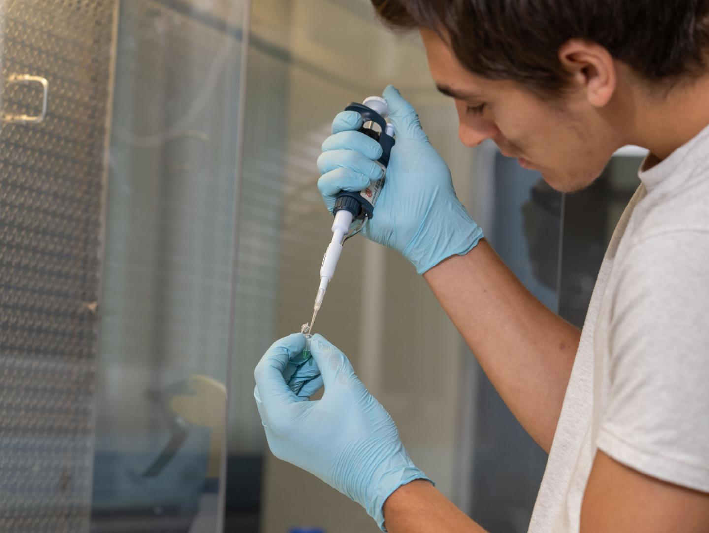 biomed lab male research student filling vials 