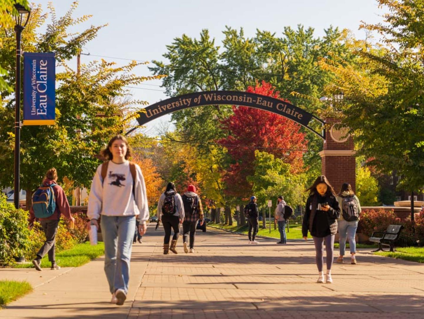 Students walking along UWEC pathway in autumn foliage 