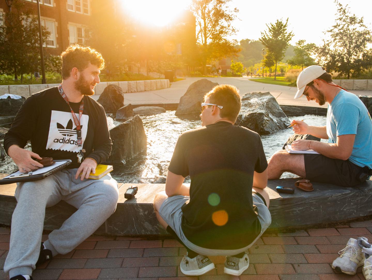 A group of student sit around a fountain at lower campus.  