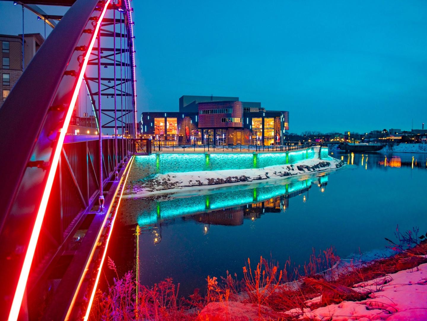 Pablo Center at sunset with colorful lights lighting up the bridge and river