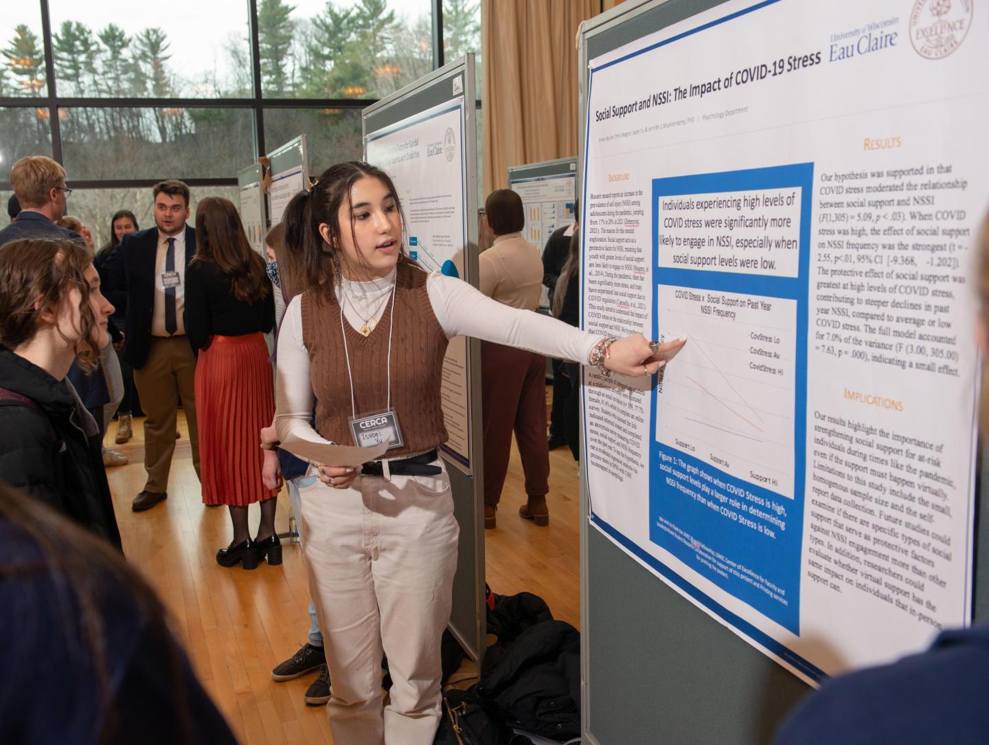 Student points to a research poster while presenting during a session