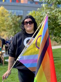 Women with short black hair holding progressive pride flag 