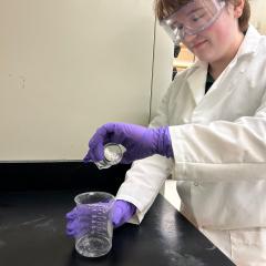 Pre-Med student Grace Cunningham pours liquid into a jar during a UWEC lab.