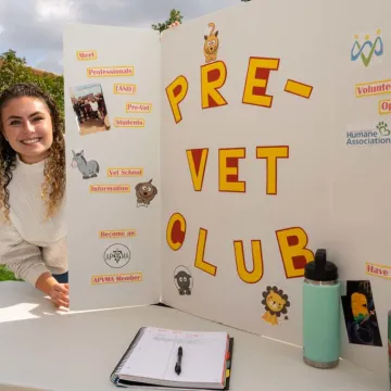 Female student at student org fest for Pre-Vet club table