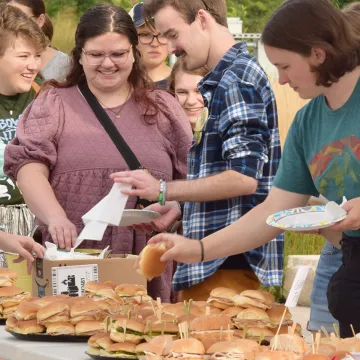 several standing students take sandwiches from platters