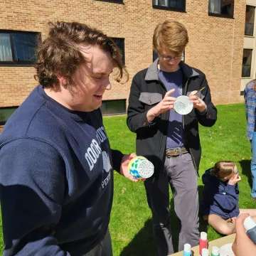 two students outside painting pots