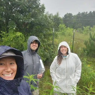 Students and faculty outside smiling in the rain