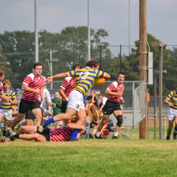 Two rugby teams chase each other on the pitch.