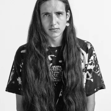 A black and white image of a person with long hair faces the camera.