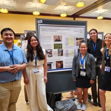 Group of student researchers smiling at poster presentation