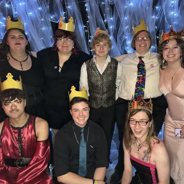 A group of students wearing crowns smile for the camera. 