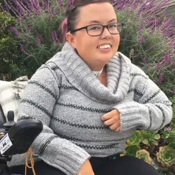 A woman in a wheelchair smiles for the camera. 