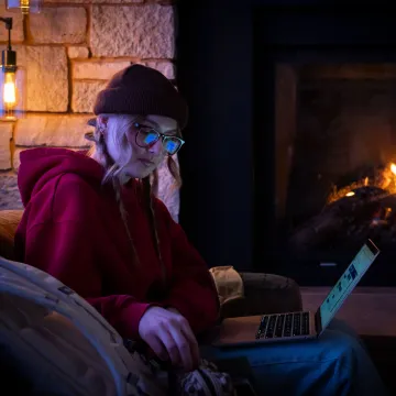 single student studying in a cozy chair by Davies Center fireplace 