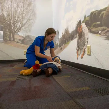 nursing student in AI simulation room with child mannequin on the floor 