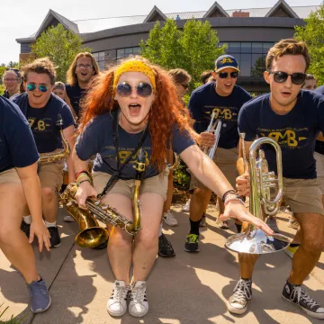 Members of the marching band cheer and pose for a photo with their instruments and matching t-shirts