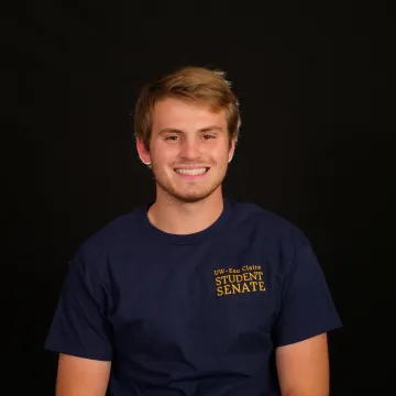 Zach smiles at camera in front of black background.