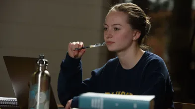 female student pensive at a library table 