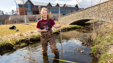female student in creek on campus
