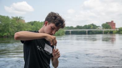 student collecting water sample at Chippewa River