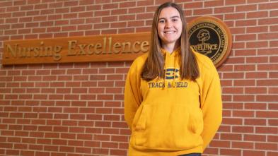 Teagan Jones in a gold Atheltics sweatshirt, smiling