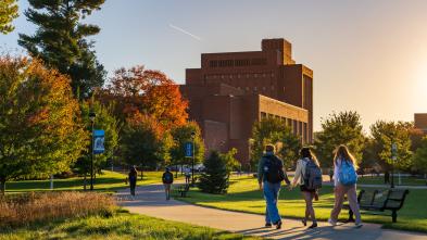 Students walk across campus as the fall sun sets.