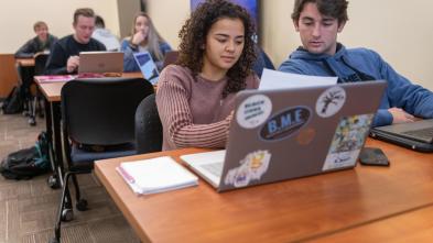 Students look at laptops during a business class.