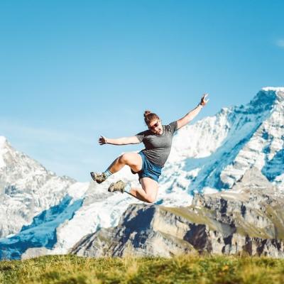 student jumping into the air in Sweden, snowy mountains behind 