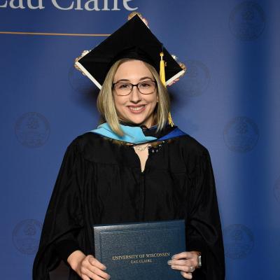 Female graduate in cap and gown, blond, glasses. Courtney Stearns