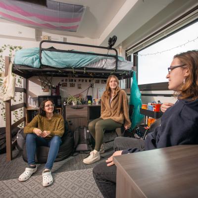 Students sitting and talking in a residence hall room.