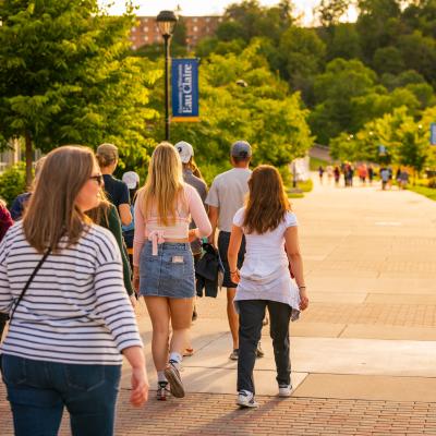 Campus visitors walk on the path towards the hill alongside the river during a campus tour.