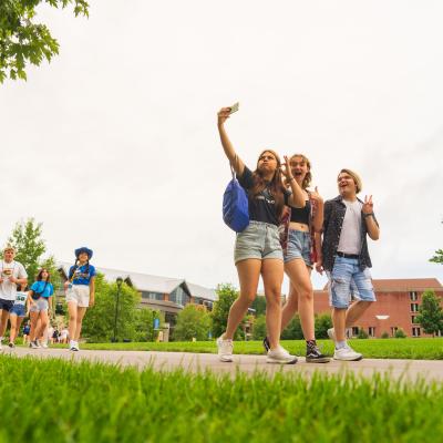 three visiting students taking a selfie on the mall sidewalk 