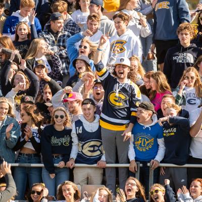 A crows of UWEC students at sport event with an excitedly cheering.