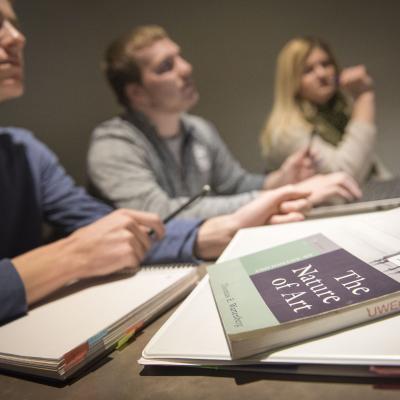 A picture of three students studying and the "The Nature of Art" on the table