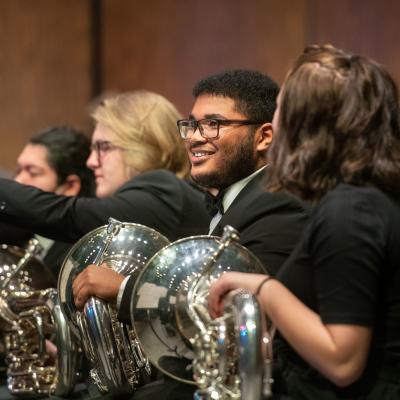 music students in horn section of orchestra during performance