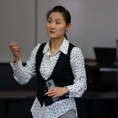 faculty standing in front of a class, using hand gestures 