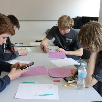 Four students use calculators and fill out worksheets at a table