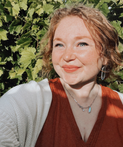 kate is posing in front of grape vines for profile image