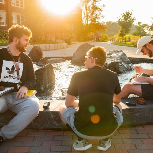 A group of student sit around a fountain at lower campus.