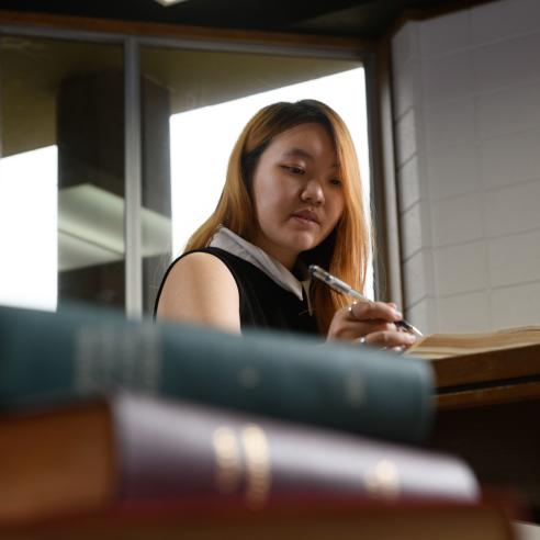 A student studying in library writing notes