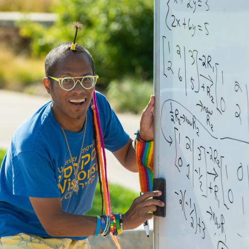 An individual writing math problem on the white board